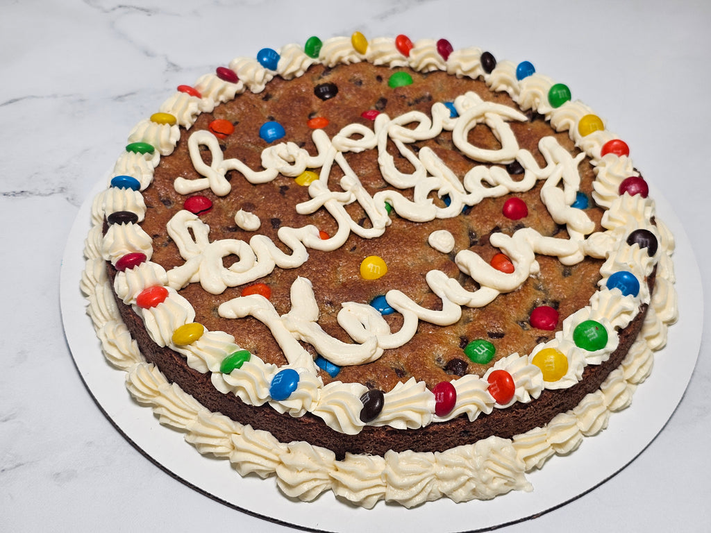 Cookie cake with 'Happy Birthday' icing and colorful candies on a marble surface